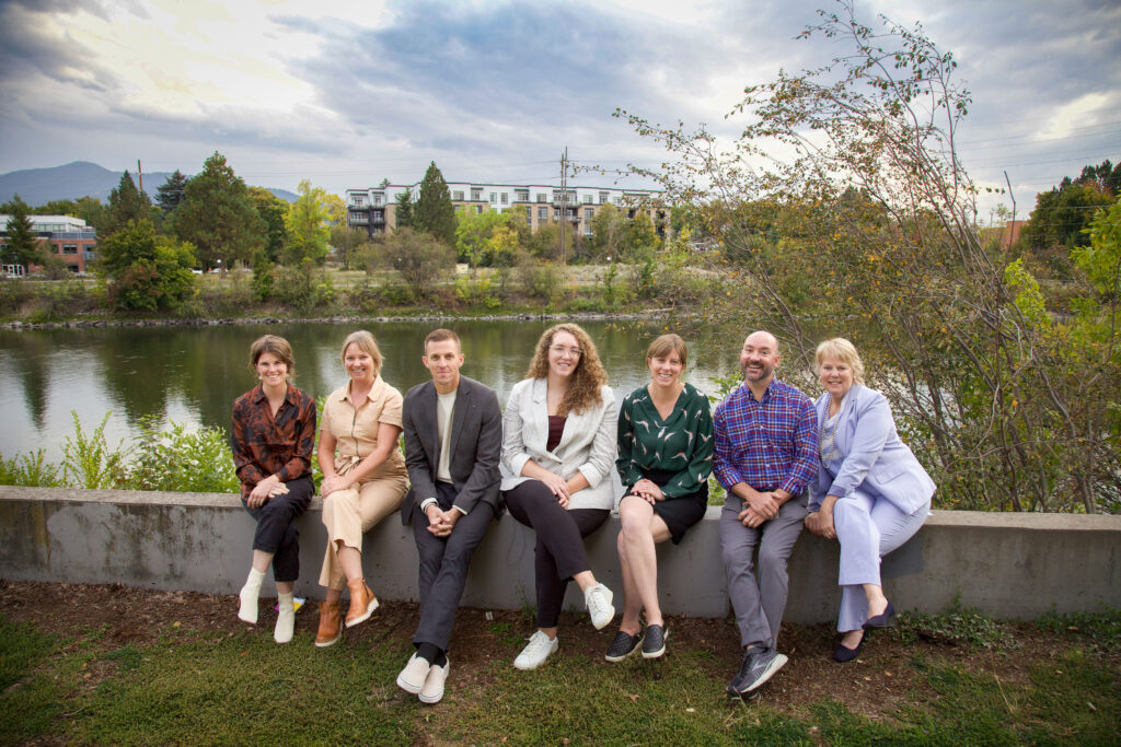 The MNA team poses with a scenic river background in Missoula Montana. The team includes five women and two men.